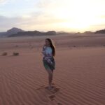 Туристка наслаждается закатом в пустыне Вади Рам